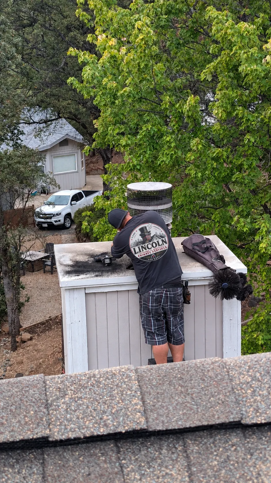 Chimney sweep cleaning a flue from a Pittsburgh rooftop